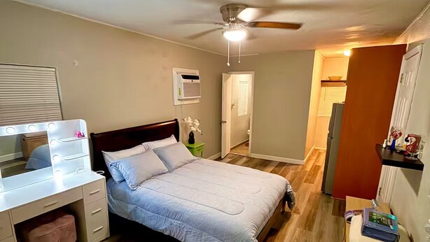 A bedroom with a bed, a vanity with lights, a ceiling fan, and a door leading to another room. - Studio. Independent entrance, AC, internet. (Miami)