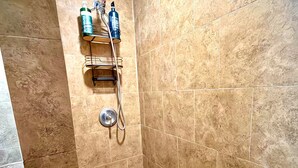 A shower area with beige tiles, a showerhead, and two bottles of shampoo. - Studio. Independent entrance, AC, internet. (Miami)