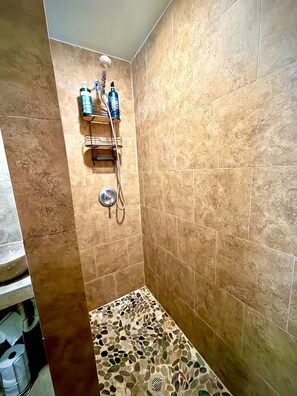 A shower area with beige tiles, a showerhead, and two bottles of shampoo. - Studio. Independent entrance, AC, internet. (Miami)