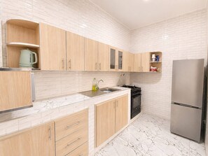 Una cocina moderna con armarios de madera, un refrigerador de acero inoxidable y una encimera de mármol.