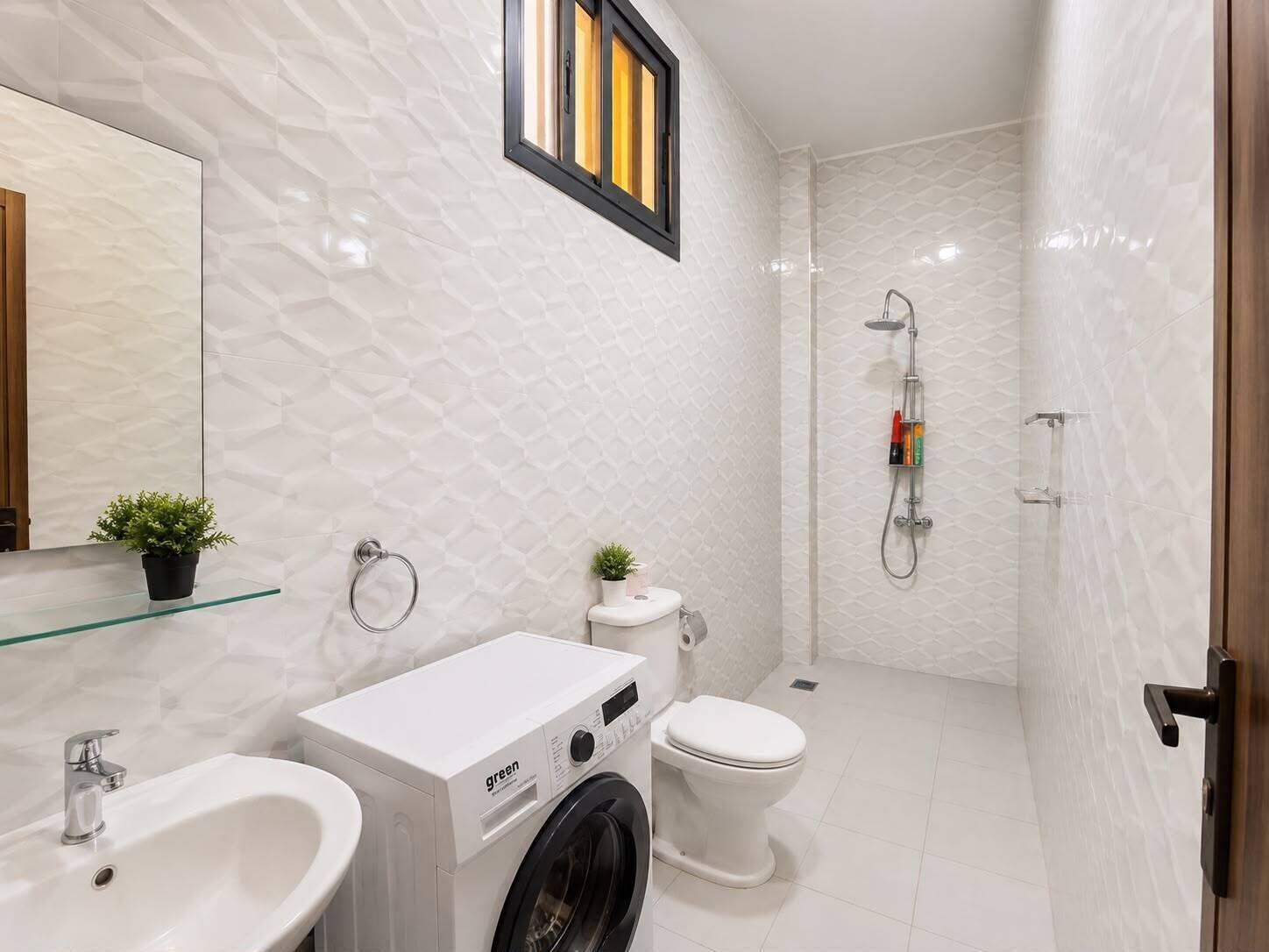 Ein kleines Badezimmer mit Waschmaschine, Toilette, Waschbecken und Dusche.
