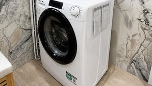 En tvättmaskin med frontmatning i ett badrum med väggar som har ett marmormönster.