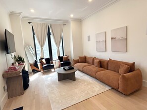 Un saló modern amb un sofà, butaques, una taula baixa i un televisor de pantalla plana.