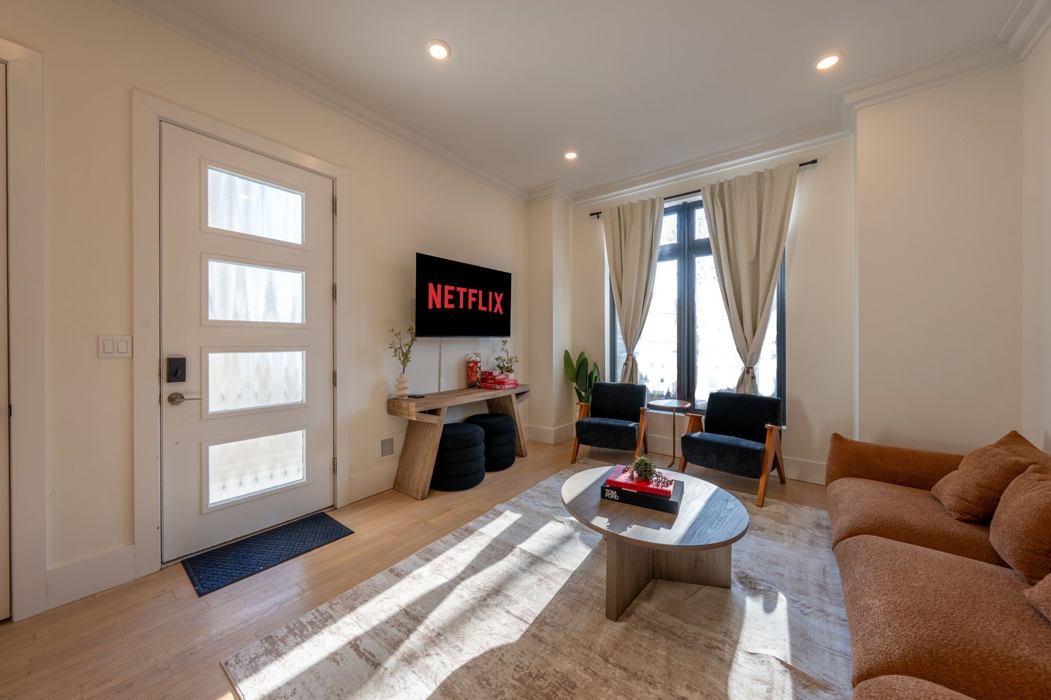 Una sala de estar moderna con un televisor de pantalla plana, una mesa de centro y asientos.