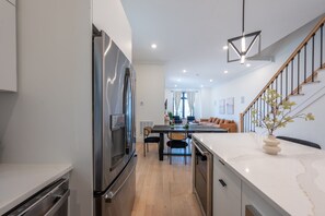 Une cuisine moderne dotée d’un four encastré, un coin repas avec une table et des chaises, et un escalier menant à l’étage supérieur.