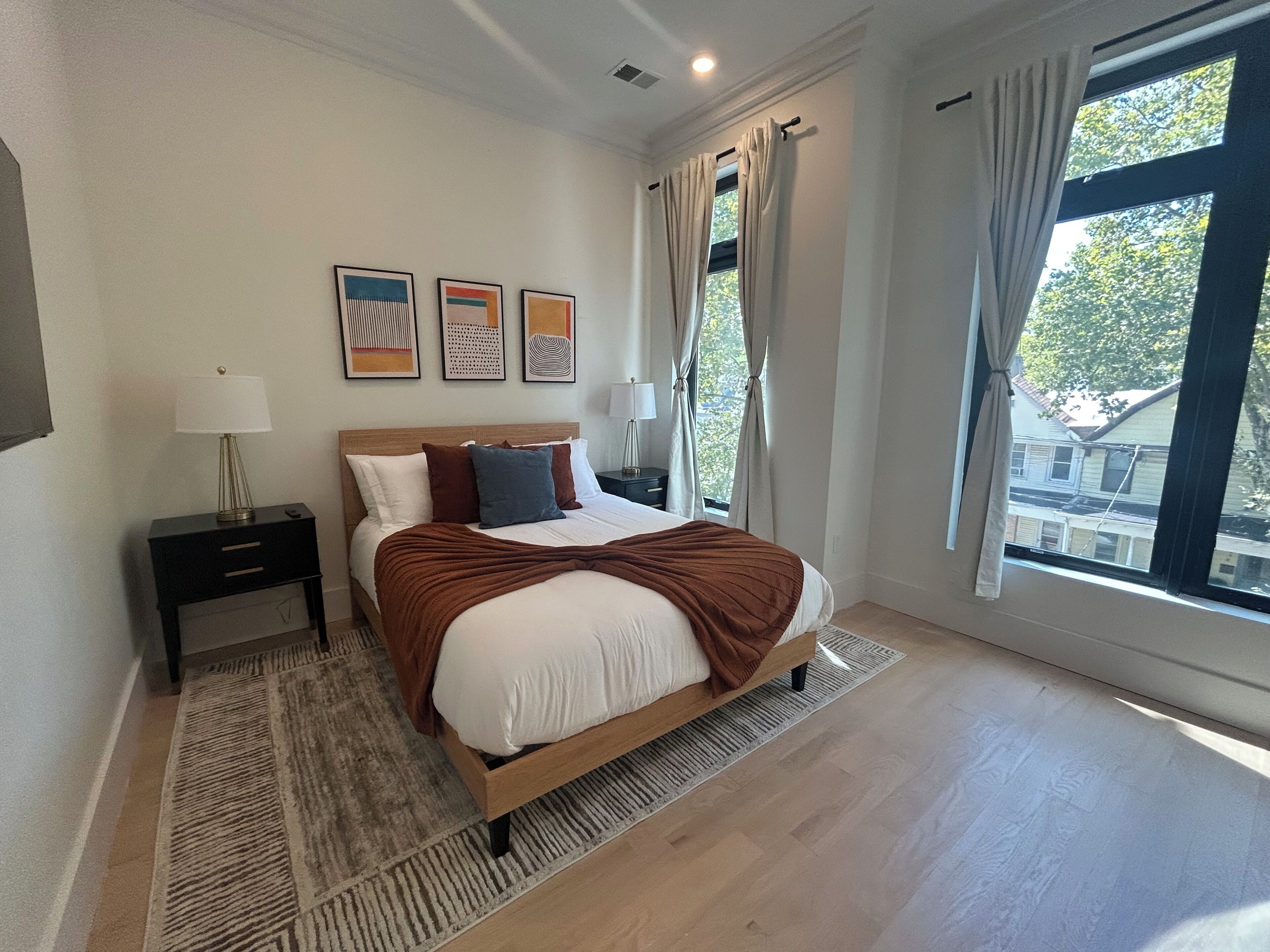 Ein Schlafzimmer mit Bett, Nachttischen, einem Teppich und Bildern an der Wand.