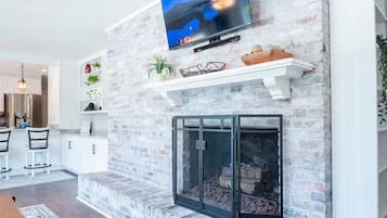 A living room with a fireplace, a mounted television, and a dining area with chairs and a table.