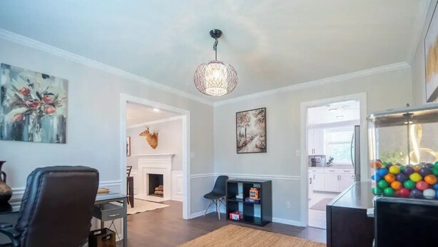 A modern living room with a fireplace, a dining area, and a kitchen visible through an open doorway.