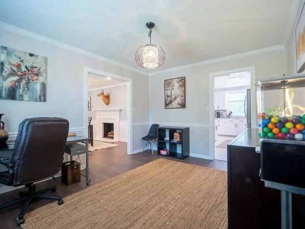 A modern living room with a fireplace, a dining area, and a kitchen visible through an open doorway.