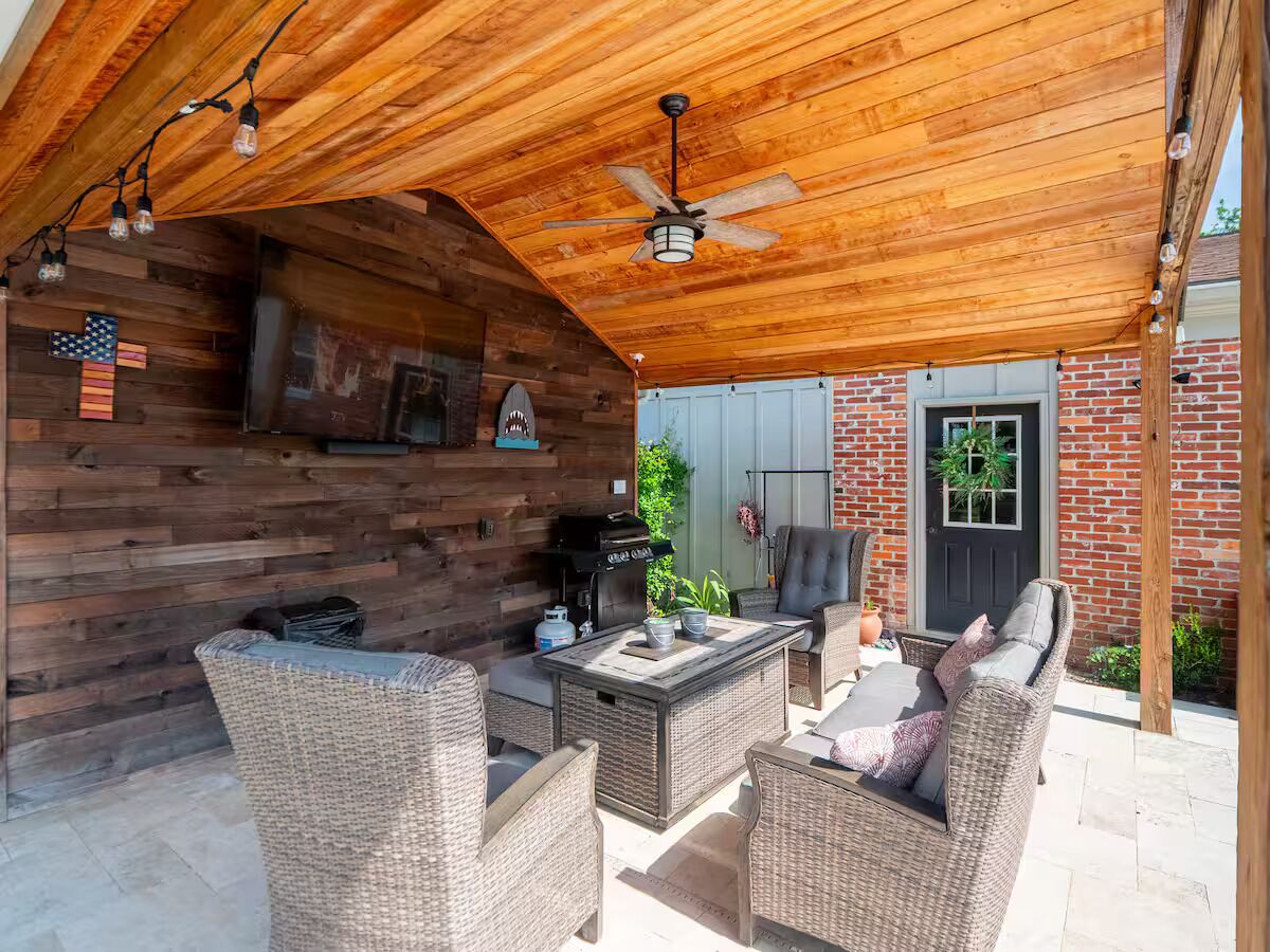 An outdoor patio with wicker furniture, a grill, and a ceiling fan.