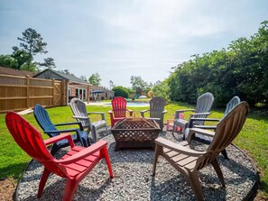 An outdoor seating area with Adirondack chairs and a fire pit.