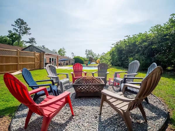 An outdoor seating area with Adirondack chairs and a fire pit.