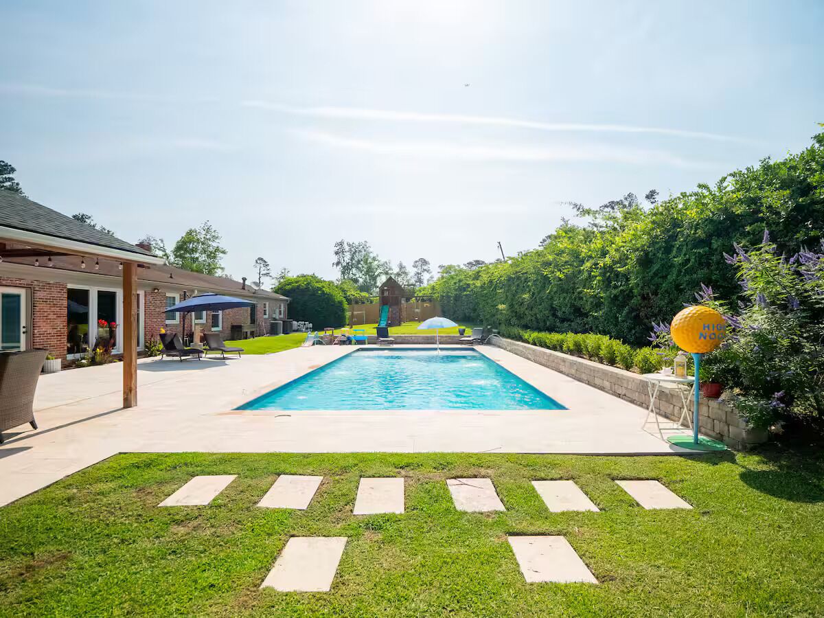 A rectangular swimming pool with a clear blue water surface, surrounded by a paved deck.