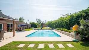 A rectangular swimming pool with a clear blue water surface, surrounded by a paved deck.