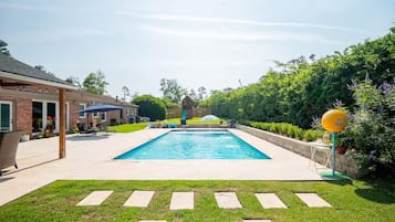 A rectangular swimming pool with a clear blue water surface, surrounded by a paved deck.