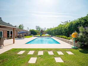 A rectangular swimming pool with a clear blue water surface, surrounded by a paved deck.