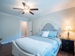 A bedroom with a bed, a nightstand, a lamp, and a ceiling fan.