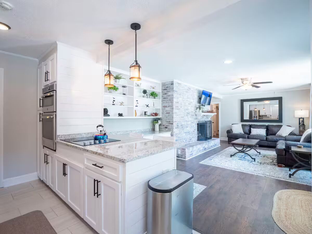 A modern kitchen with white cabinetry, a granite countertop, and pendant lighting.