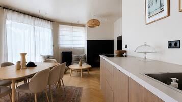 A modern kitchen with a built-in sink, a dining area with a table and chairs, and a living space with a sofa and a fireplace.