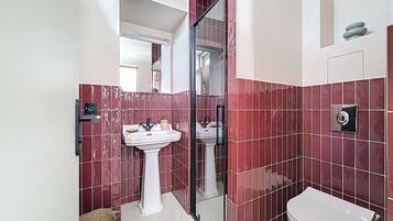 A bathroom with a white sink, a toilet, and a glass shower enclosure.