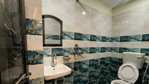 Un baño con lavamanos, espejo, inodoro y un balde.