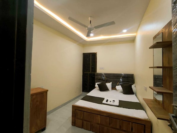 A bedroom with a bed, a ceiling fan, and a wooden cabinet.