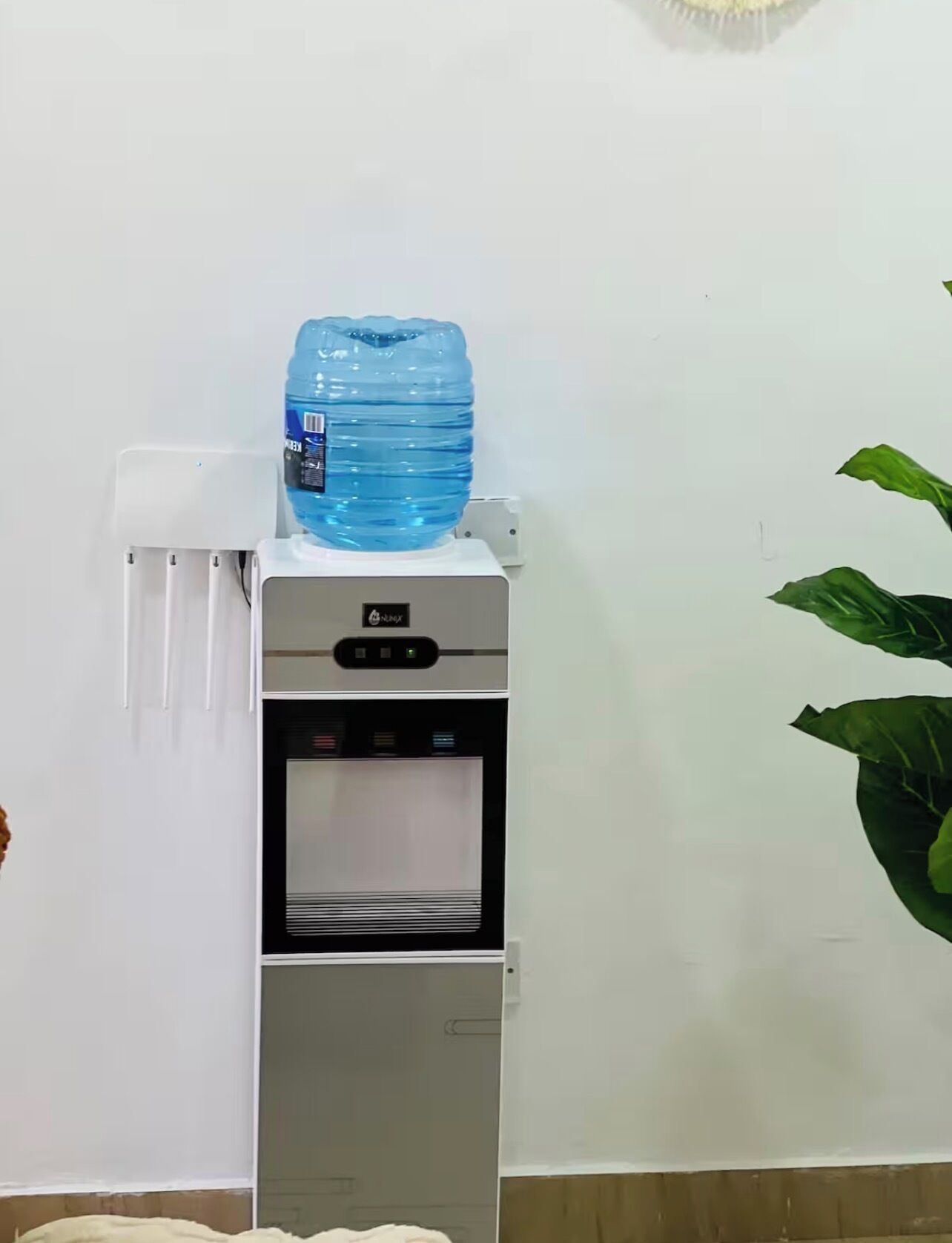 A water dispenser with a large water bottle on top, a control panel, and a water bottle holder.