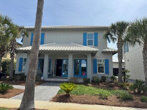 A two-story building with a tiled roof, blue shutters, and a paved entrance area with plants. - Spacious 5-bedroom, 5.5 bath house in Miramar Beach-Caribe Subdivision (Miramar Beach)
