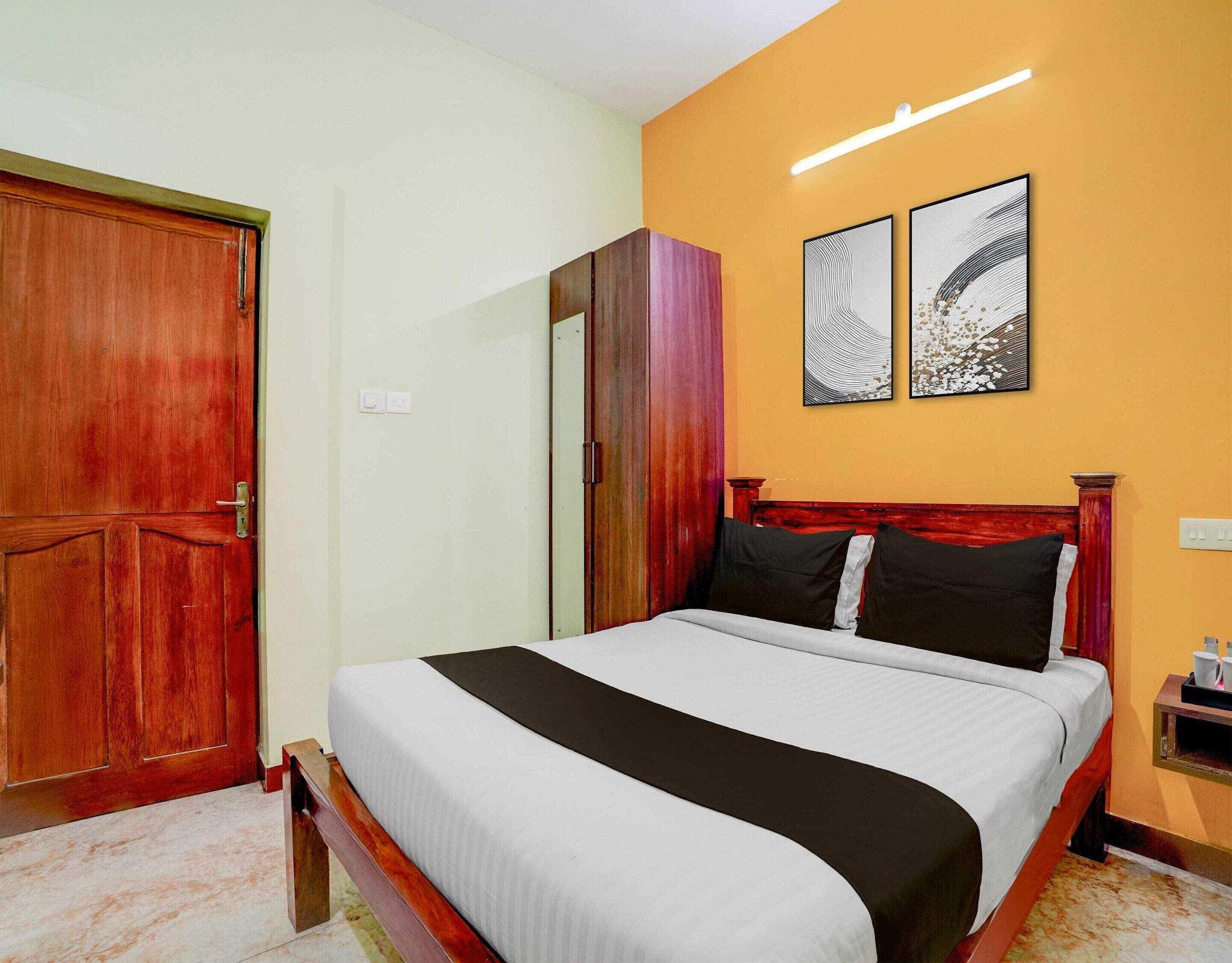 A hotel room with a bed, a wardrobe, and two wall-mounted artworks.