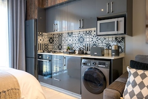 A compact kitchen with a microwave, a washing machine, and a coffee maker. - Slick Studio at Ocean Club H24 (Ballito)