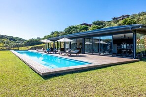 Une maison moderne dotée d’une piscine, d’un espace salon extérieur et offrant une vue sur le paysage environnant.