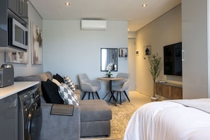 A modern, compact living space with a kitchenette, a dining area, and a bedroom. - Slick Studio at Ocean Club H24 (Ballito)