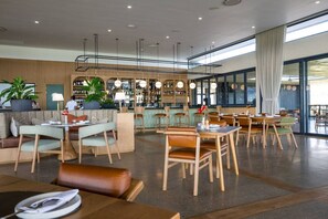 Ein modernes Restaurant mit Barbereich, Sitzmöglichkeiten und großen Fenstern.