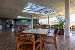 A spacious indoor area with a high ceiling, wooden furniture, and a television screen. - Slick Studio at Ocean Club H24 (Ballito)