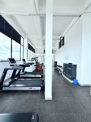 Ein Fitnessstudio mit Laufbändern, Gewichten und einem großen Fenster mit Blick auf eine Stadtlandschaft.