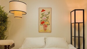 A hotel room with a bed, a chair, a hanging lamp, a framed floral artwork, and a tall floor lamp. - Jamil station 10 mind. 9 line subway station. Lottery world tower (Seoul)