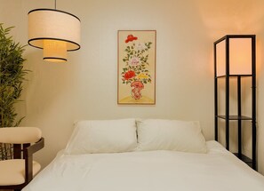 A hotel room with a bed, a chair, a hanging lamp, a framed floral artwork, and a tall floor lamp. - Jamil station 10 mind. 9 line subway station. Lottery world tower (Seoul)