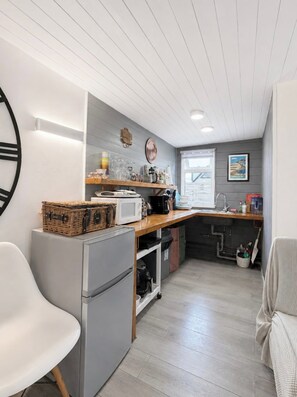 A compact kitchen with a refrigerator, microwave, and wooden countertop. - The Cabin At The Beach (Seasalter)
