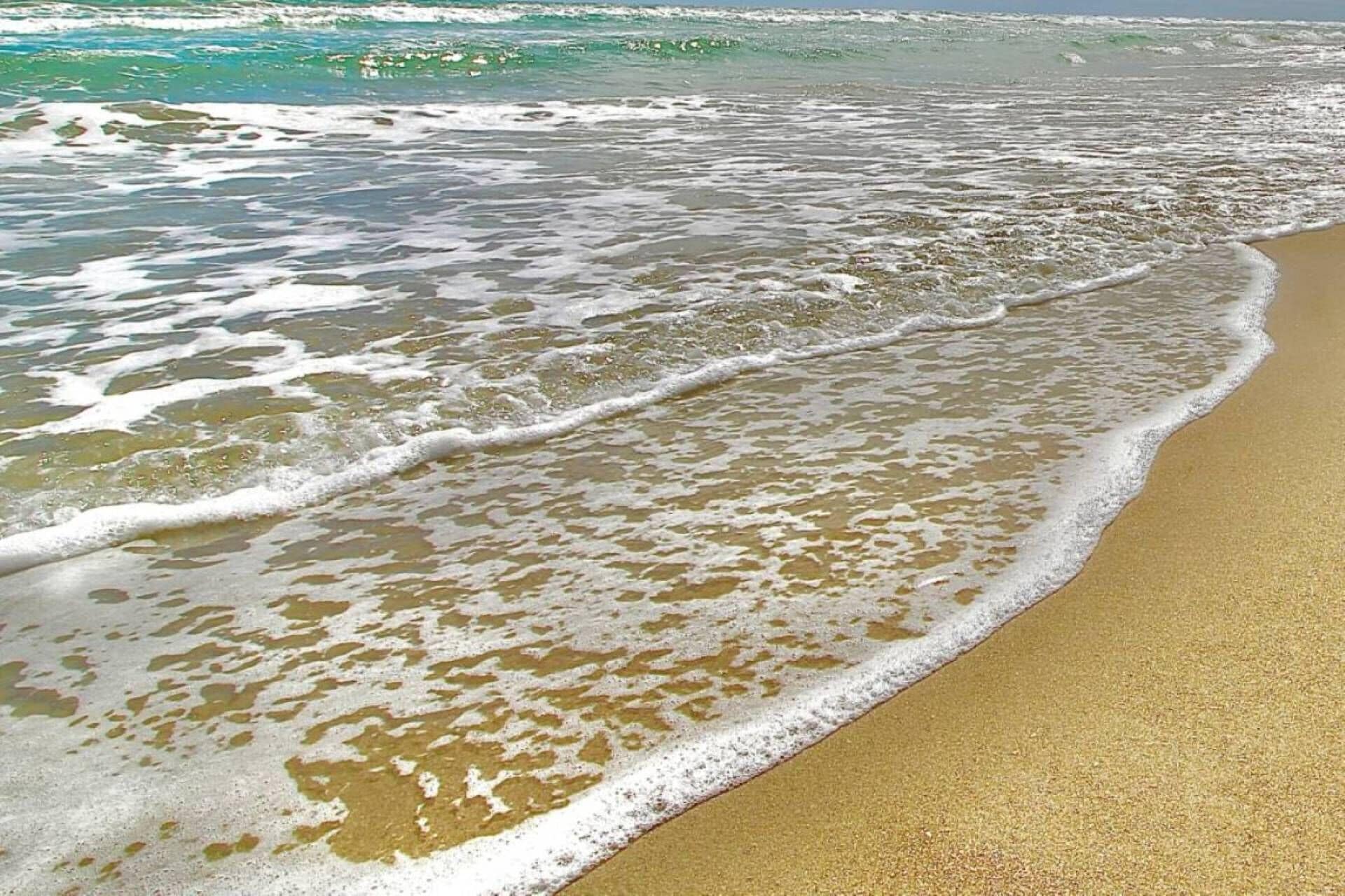 A sandy beach with gentle waves lapping at the shore.