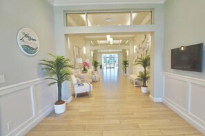 A spacious hallway with a high ceiling, wooden flooring, and a view into a dining area. - Seabreeze - Beautiful Newly Renovated 2 Bed Condo - Oceanfront Community - Golf Course - Resort Pool (Fort Pierce)