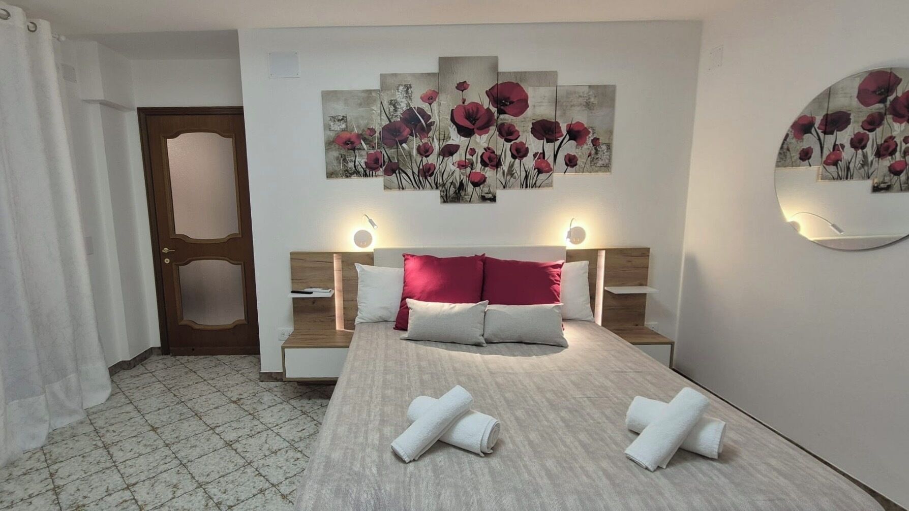 A hotel room with a bed, two bedside tables, a headboard, and a wall-mounted artwork.