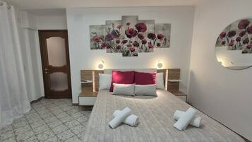 A hotel room with a bed, two bedside tables, a headboard, and a wall-mounted artwork.