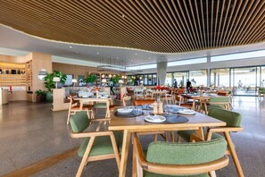 A spacious indoor dining area with multiple tables and chairs, a reception desk, and a view of the outdoors. - Gorgeous Ocean Club Studio G21 (Durban)