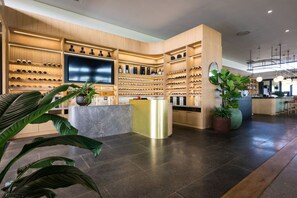 Um saguão de hotel moderno com uma adega de vinhos, um balcão de recepção e uma grande tela de TV.