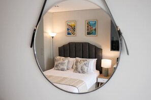 A bedroom with a bed, two wall-mounted lamps, and two framed pictures. - Gorgeous Ocean Club Studio G21 (Durban)
