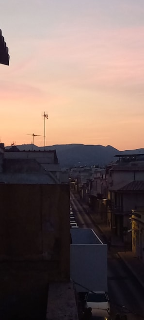 A street view at dusk with buildings and a mountain in the background. - Cozy 1-bedroom townhome in tranquil Avola with AC (Avola)
