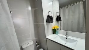 A bathroom with a white sink, a toilet, a shower, and a mirror with a towel rack.
