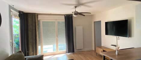 A modern living room with a sofa, a coffee table, a TV, and a ceiling fan.