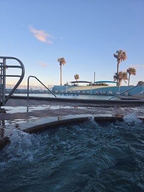 A pool area with water jets, lounge chairs, and palm trees. - Oceanfront Paradise at Fountain Beach Resort / Daytona Beach (Daytona Beach)