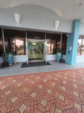 Ein Hotel Eingang mit einer nummerierten Tür, einem gefliesten Weg und Topfpflanzen.